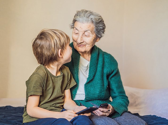 Old woman uses an old phone, boy uses a smartphone Old woman uses an old phone, boy uses a smartphone