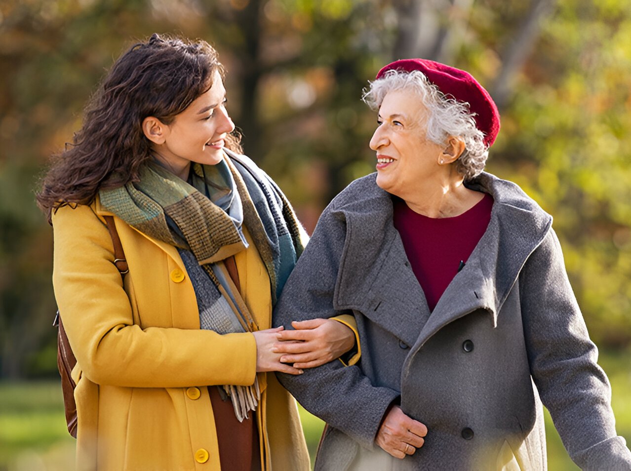 Senior woman walking with granddaughter in park during autumn
