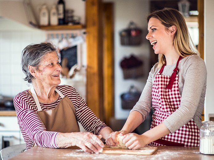 An elderly grandmother with an adult granddaughter at home, baking. An elderly grandmother with an adult granddaughter at home, baking.